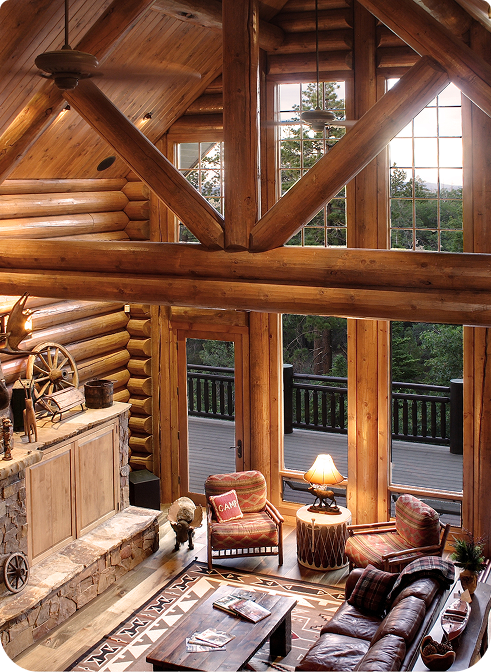A stunning log cabin made of rich red cedar nestled among tall pine trees under a clear blue sky.