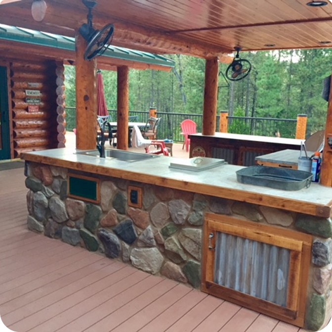 A stunning log cabin made of rich red cedar nestled among tall pine trees under a clear blue sky.